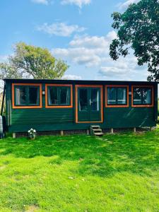 a green and orange train car in a field at Walland Cottage Romney Retreat in Old Romney