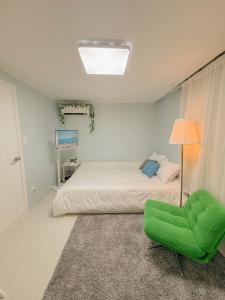 een slaapkamer met een bed en een groene stoel bij Ahyeon Station 10-minute walk Cozy Stay in Seoul