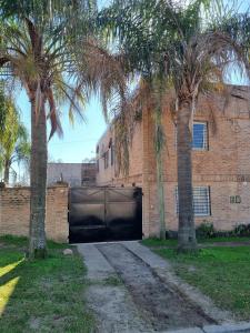 a brick building with a garage with palm trees in front at Pindó II - Expresión de buen gusto in Concordia
