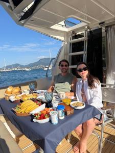 a man and woman sitting at a table with food on a boat at Iate de luxo Intermarine 44 pés in Ilhabela