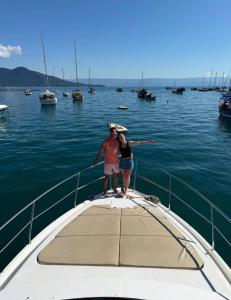 a man and a woman standing on the front of a boat at Iate de luxo Intermarine 44 pés in Ilhabela +3 photos