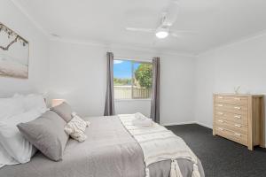 a white bedroom with a large bed and a window at Beach Shack No. 5 in Crescent Head