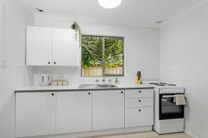 a white kitchen with white cabinets and a window at Beach Shack No. 5 in Crescent Head