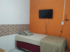 a bedroom with a bed with a flat screen tv on the wall at Casarão 3 quartos com ar e garagem in Belém