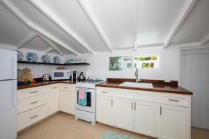 a kitchen with white cabinets and a white refrigerator at Lillian's Cottage cottage in Harbour Island