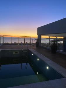a swimming pool on top of a building with a sunset at Bello y confortable Apartamento con Parking in Encarnación +25 photos