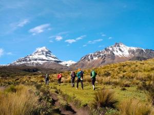 a group of people walking on a trail with mountains in the background at Hostal Casa Cotopaxi in Latacunga