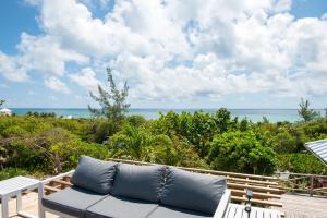 a couch on a deck with the ocean in the background at Utopia House home in Savannah Sound