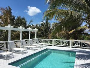 a swimming pool with two chairs and a swimming pool at Alfred House home in Governorʼs Harbour