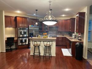 Una cocina con gabinetes de madera y una isla con taburetes de bar. en LUX homes, en Fort Washington