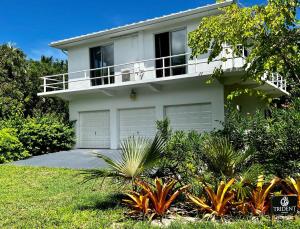 une maison blanche avec un balcon au-dessus dans l'établissement Trident Cottage cottage, à Palmetto Point