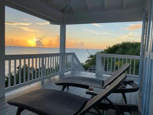 eine Veranda mit zwei Stühlen und einem Tisch und dem Meer in der Unterkunft Palm Bluff cottage in Gregory Town