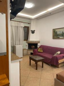 a living room with a purple couch and a fireplace at Guesthouse Joal in Përmet +11 photos