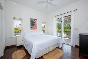a white bedroom with a bed and two windows at Sand Dollar Cottage cottage in Rock Sound +19 photos
