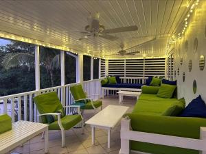 a porch with a green couch and chairs on it at Bahama Mama home in Governorʼs Harbour