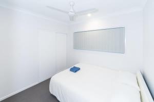 a white bedroom with a bed and a ceiling fan at Brand New 4BR Family Oasis Easy Brisbane Access in Park Ridge