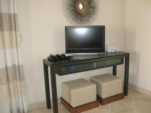 a television on a desk with two stools at Sky Beach Club Bungalow 2 cabin in Governorʼs Harbour