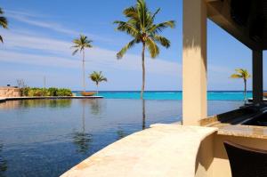 a swimming pool with palm trees and the ocean at Sky Beach Club Bungalow 2 cabin in Governorʼs Harbour +18 photos