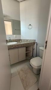 een badkamer met een toilet, een wastafel en een spiegel bij Apartamento no Centro em Poços de Caldas in Poços de Caldas +12 foto's