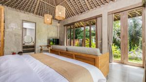 a bedroom with a bed and a television and windows at Tulip Villa Ubud in Ubud
