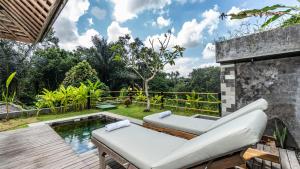 an outdoor patio with a pool and two couches at Tulip Villa Ubud in Ubud