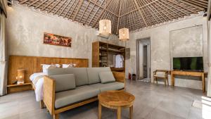 a bedroom with a bed and a couch and a tv at Tulip Villa Ubud in Ubud
