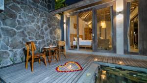a patio with a table and chairs next to a pool at Tulip Villa Ubud in Ubud