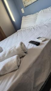 a bed with towels and a remote control on it at Apart 202 smartTV WIFI AC 100M Cariri Shop in Juazeiro do Norte