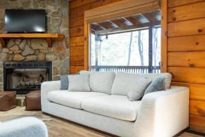 a living room with a white couch and a stone fireplace at Aska's Cozy Corner Cabin in Cherry Log