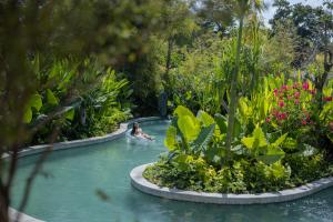 a person swimming in a pool in the water with plants at Sumitra Luxury Villas & Resort by Pramana in Sanur