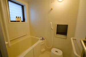 a bathroom with a tub and a toilet and a window at 金柑和屋 in Osaka +51 photos