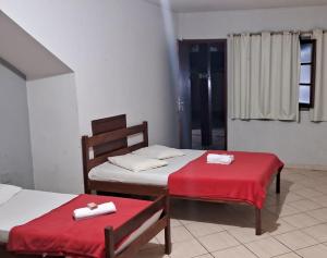 瓜拉派瑞Pousada Paraiso - Prédio 124的宿舍间的两张床,配有红色的床单和毛巾