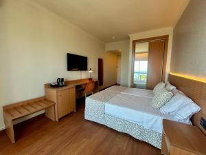 a bedroom with a bed and a desk and a television at Hotel Santa Rosa in Torrox Costa