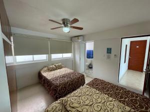 une chambre avec deux lits et un ventilateur de plafond dans l'établissement Casa Blanca, à Acapulco