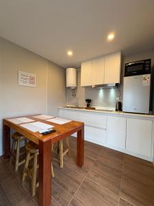 a kitchen with a wooden table and white cabinets at Cabañas Punta Virgen in Curacautín