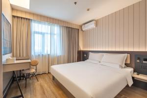 a hotel room with a bed and a desk and a window at Hanting Hotel Beijing Changping Zhengfu Street in Beijing