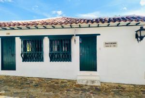 a white house with green doors and a red roof at La Posada de Jose Antonio in Villa de Leyva