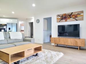 a living room with a couch and a large flat screen tv at Marina Park Apartments Whitianga in Whitianga