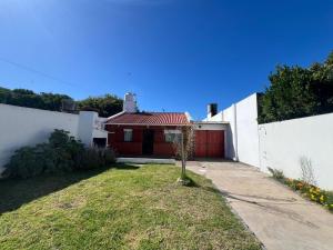 a small house with a red garage in a yard at Casa playa Quequen a dos cuadras del mar in Quequén