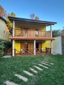 a yellow house with a balcony and a yard at Mansion SP, Heated Pool, PS5, Einstein USP in Sao Paulo