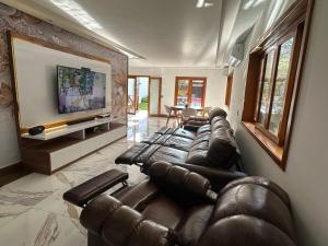 a living room with leather couches and a flat screen tv at Mansion SP, Heated Pool, PS5, Einstein USP in Sao Paulo