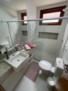 a white bathroom with a sink and a toilet at Villaggio Super Aconchegante in Marau +28 photos