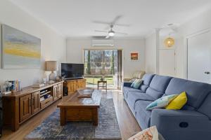 a living room with a blue couch and a tv at Jacks Corner - 10 Marjory Street, Normanville in Normanville