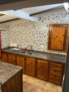 Una cocina con gabinetes de madera y un fregadero. en Hogar Lejano Cabañas y Río - Huerta Grande - Sierras de Córdoba, en Huerta Grande