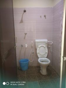 a bathroom with a toilet and a blue bucket at Royal Residency in Mahabalipuram