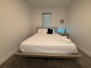 a bedroom with a bed with white sheets and a clock at Upscale Niagara Falls Getaway - BRAND NEW in Niagara Falls