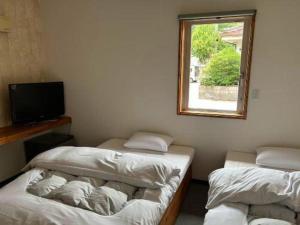 津和野町にあるBusiness Hotel Tsuwanoのベッド2台、テレビ、窓が備わる客室です。