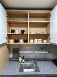 a kitchen with a sink and shelves with cups and dishes at Cozy Duplex Rental 10 sec from Hongik stn in Seoul