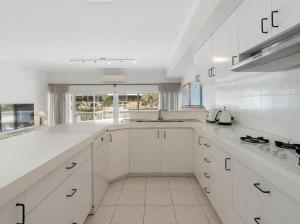a large white kitchen with white cabinets and a sink at Port Sails Escape in Mandurah +8 photos