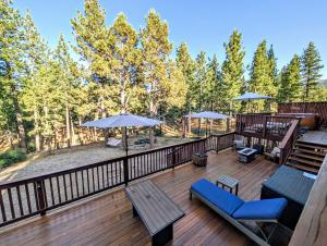 a deck with chairs and tables and umbrellas at Bel Air of Big Bear - Fun & Tech & Massive Cabin in Big Bear City